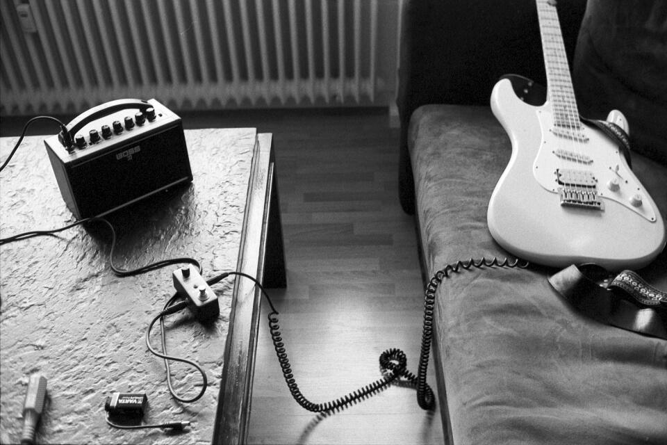 My strat-like guitar on a sofa, connected per cable to the mini looper pedal and the Boss Katana Mini amplifier.