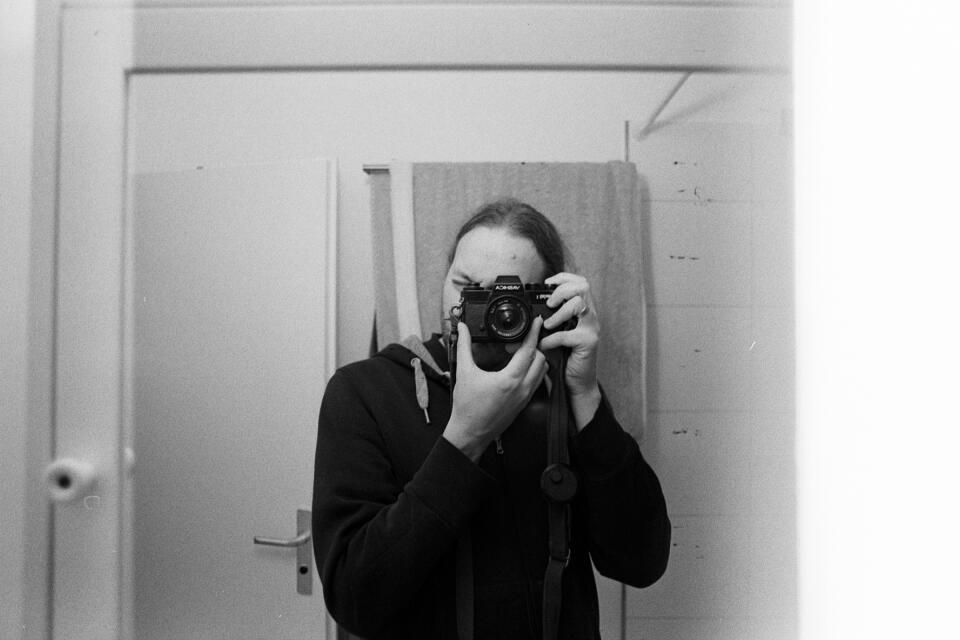 Self-portrait in a mirror, holding the Yashica FR1 to my eye. A pronounced all-white strip is on the right quarter of the image.