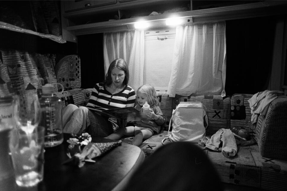 Nicole and Zoe reading a book together inside the camper in the evening.