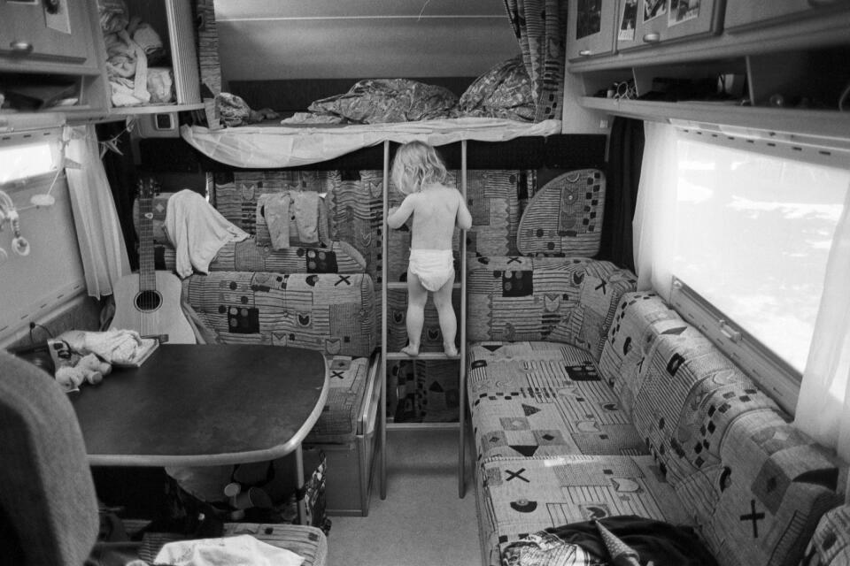 Zoe inside our campervan on the ladder that connects to the overhead bed.