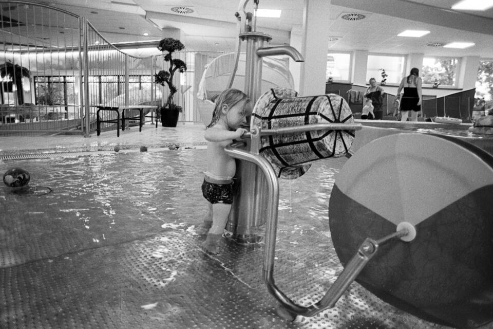 Zoe inside a swimming pool, looking into an installed bucket play thingy.