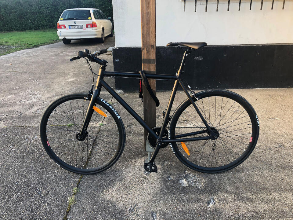 My new black singlespeed roadbike leaned and locked to a wooden pole.