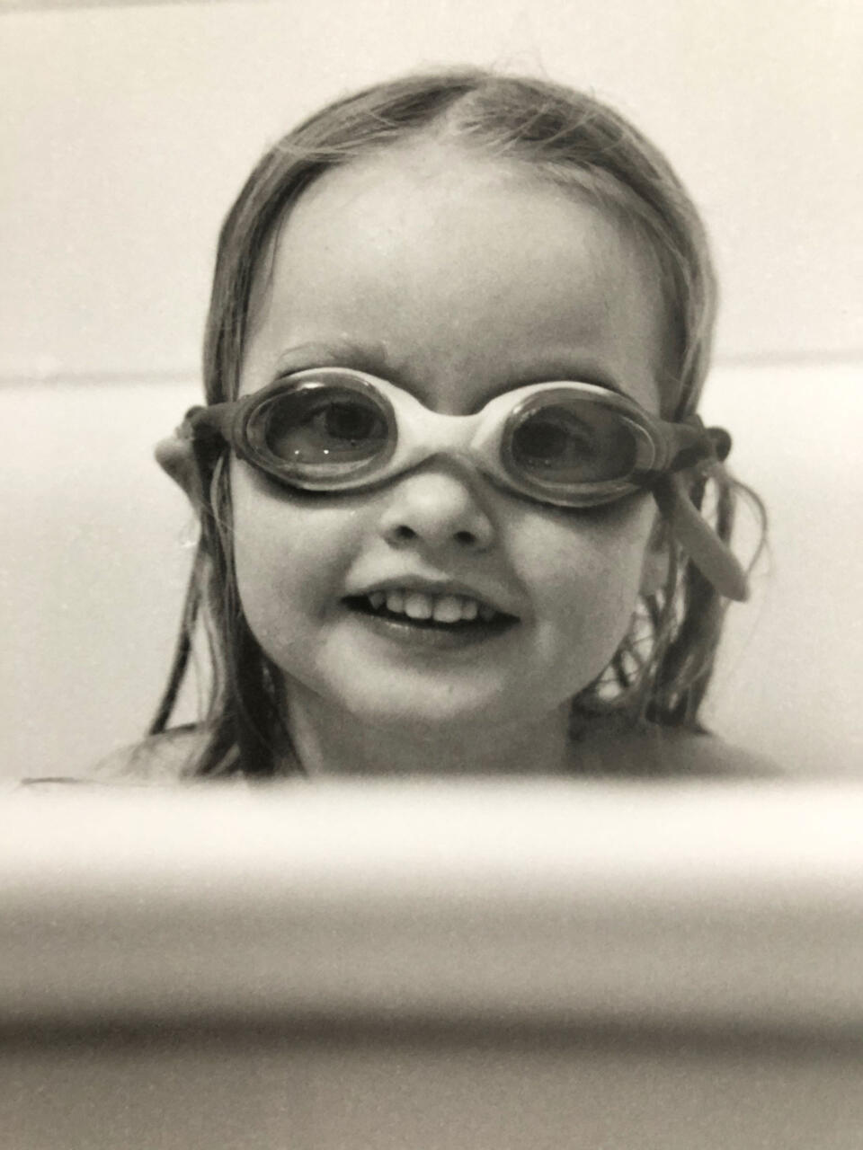 Crop of Zoe (3) in the bathtub, with swimming goggles on.