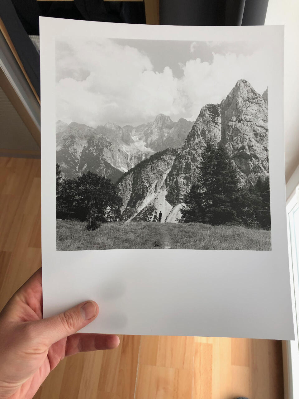 A partly cloudy landscape image of mountains with a little person in the bottom middle of the frame.